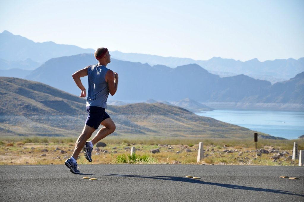 man running on sidewalk with mountains in background