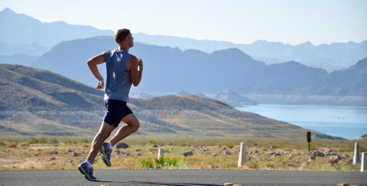 man running on sidewalk with mountains in background