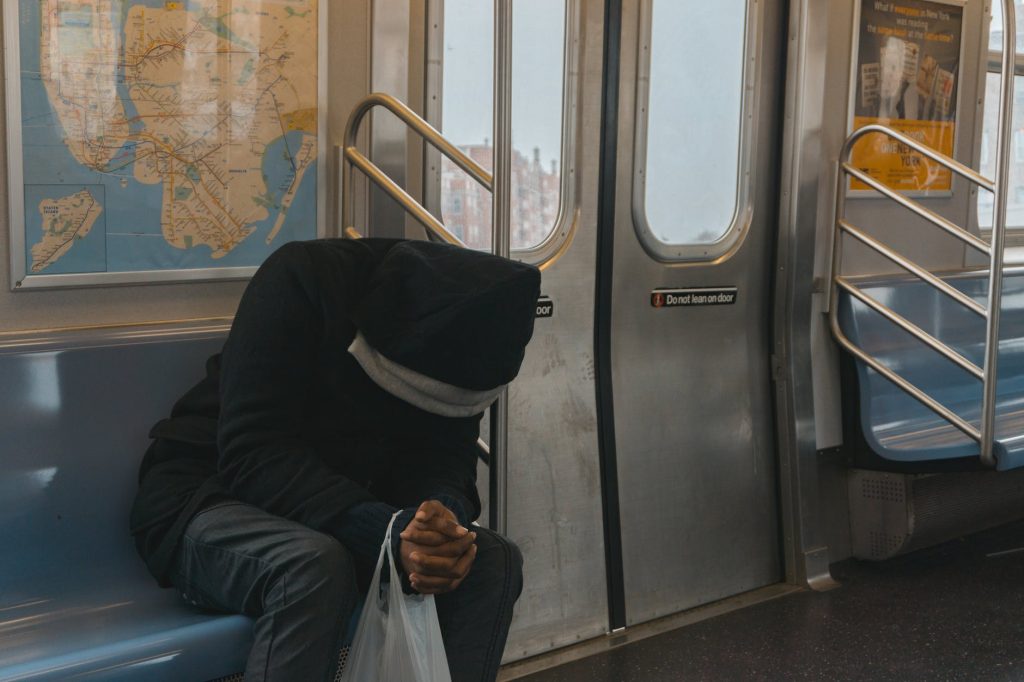 man with head down sitting on a train