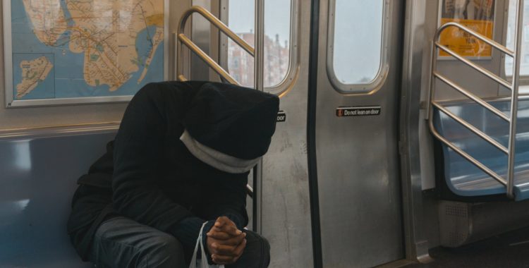 man with head down sitting on a train
