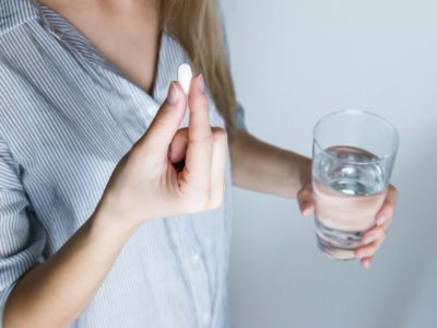 woman holding a pill and glass of water