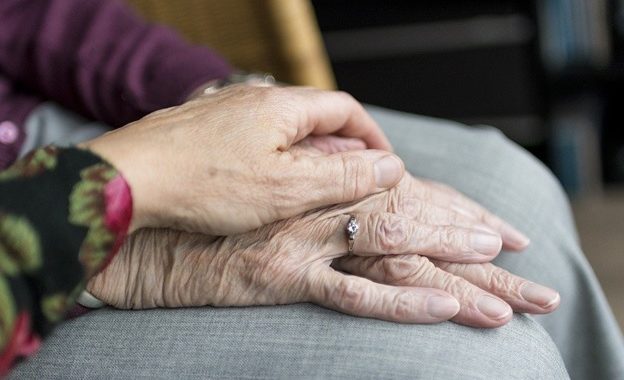 A woman holding the hand of an elderly lady