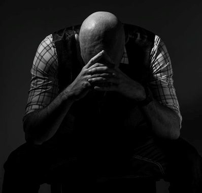 A man feeling depressed and sitting with his head in his hands.