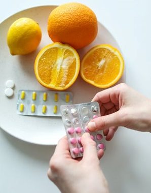 A person taking out tablets and placing them on a plate along with oranges