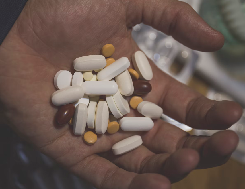 A person holding medication pills in their hand