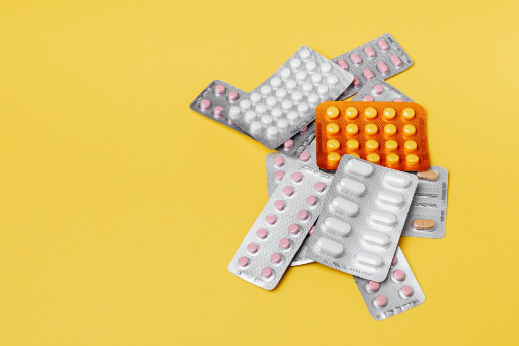 Group of various pills on yellow background