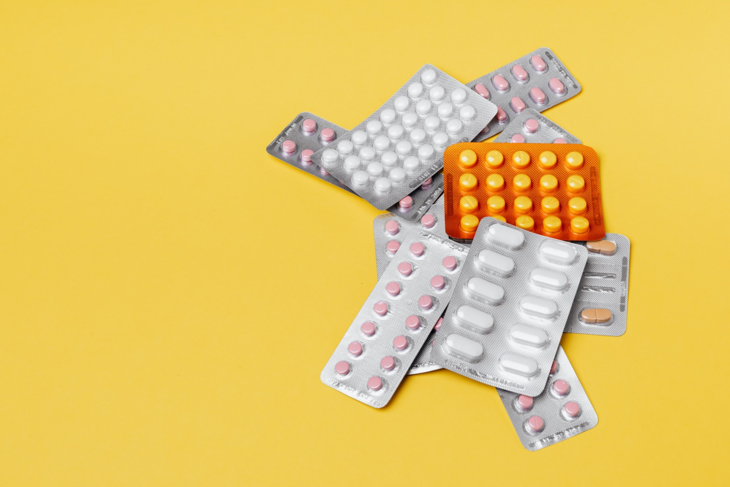 Group of various pills on yellow background