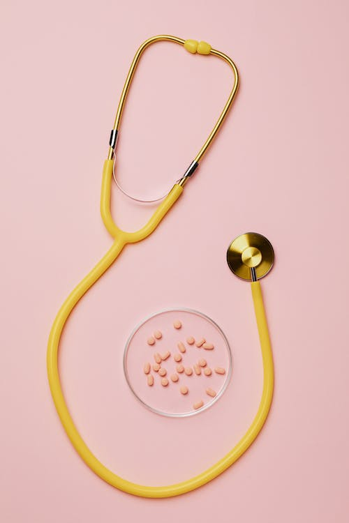 An image of pills and a stethoscope on a pink background 
