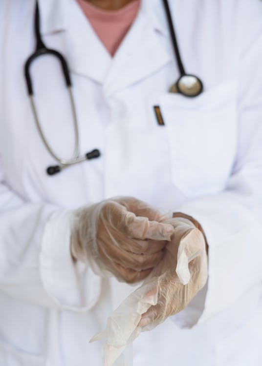 An image of a doctor wearing gloves with a stethoscope through his neck