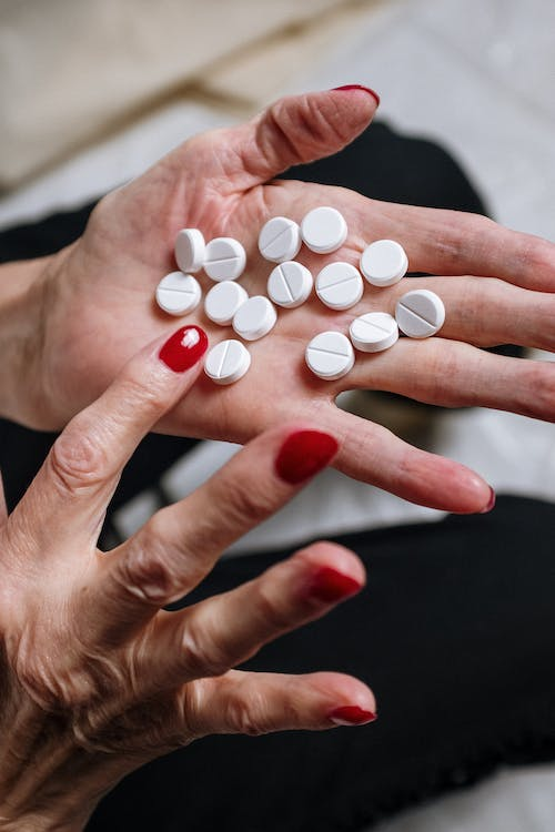 An image of white pills in a woman’s hand