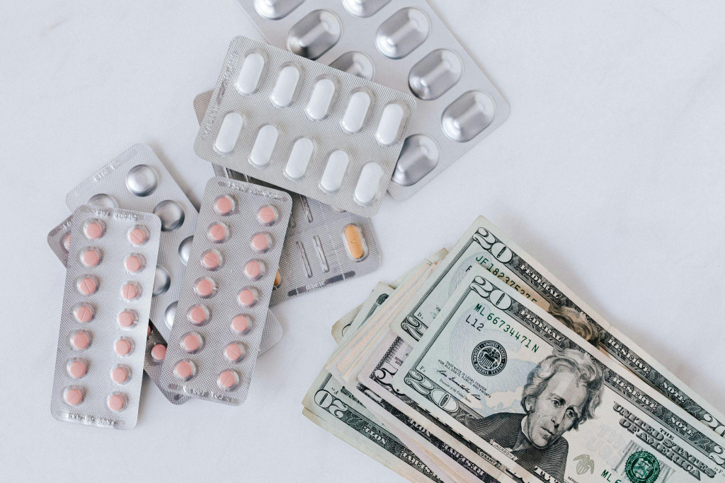 a pile of money next to med blisters