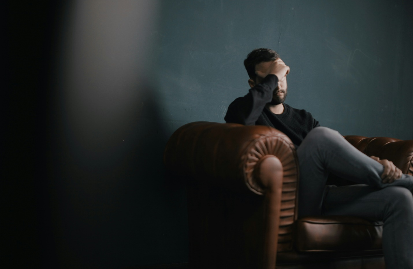 a man sitting on a sofa holding his head