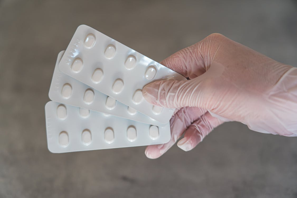 Person holding a white blister pack of medication.