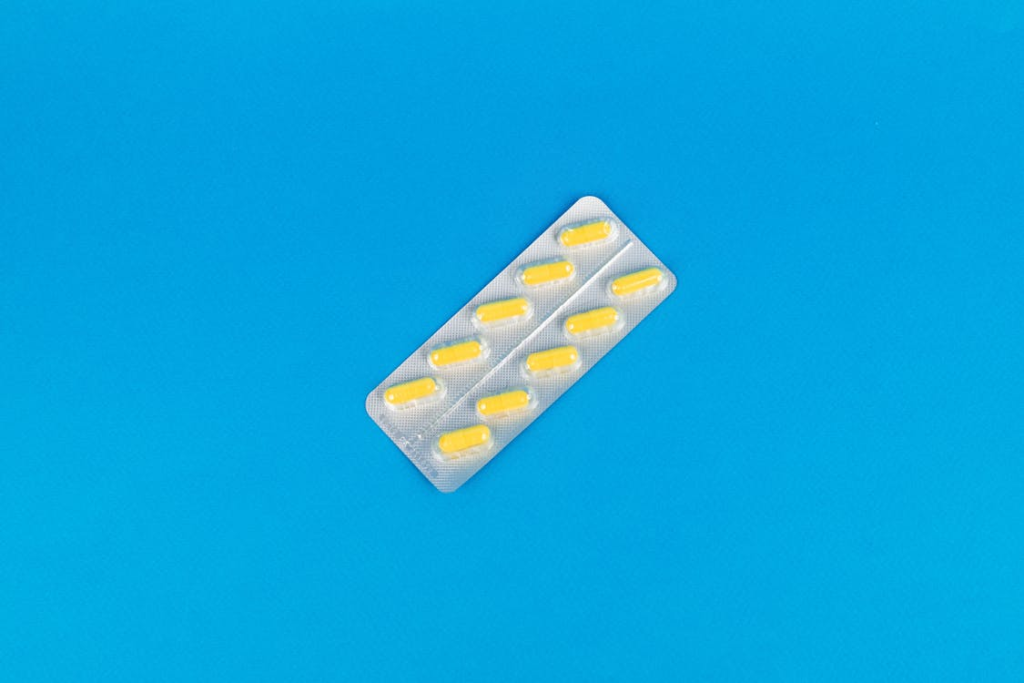 Yellow medicine capsules scattered on a blue surface.