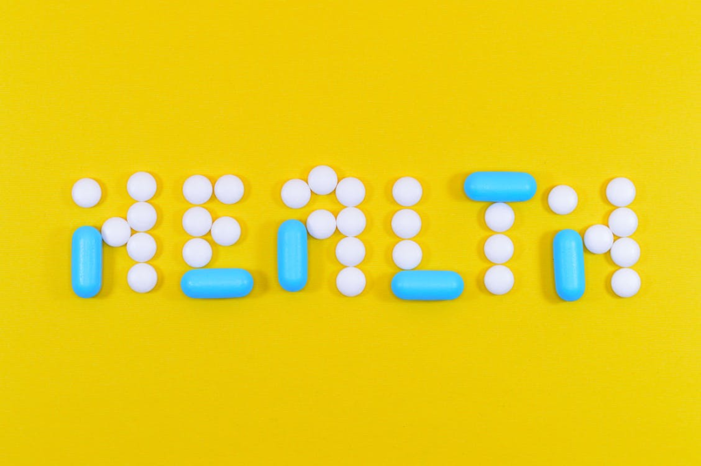 White and blue health pill and tablet letter cutout on a yellow surface.