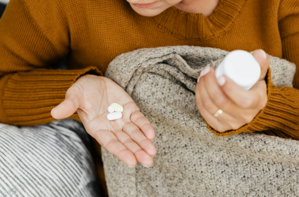 Person holding pills and a bottle