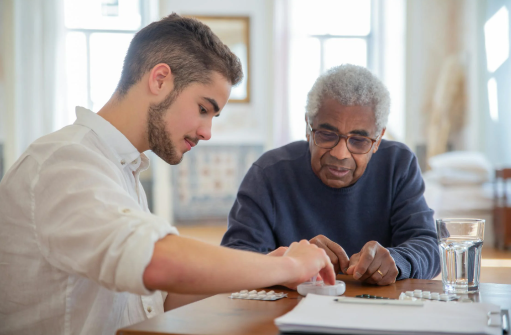 Young man assisting an older man with medication