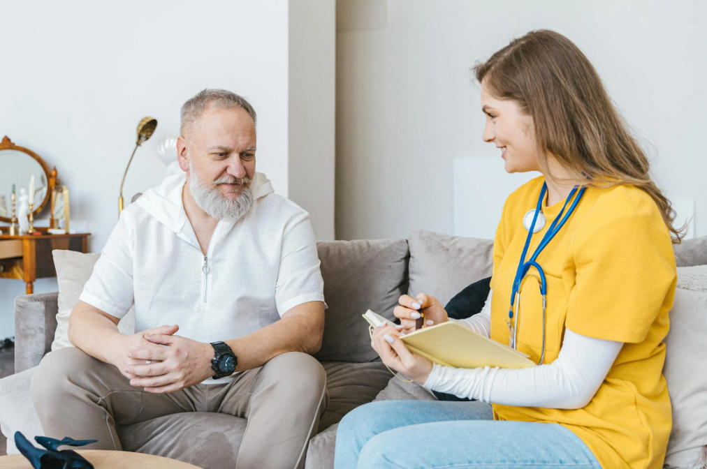 Caregiver taking notes while talking to a senior man
