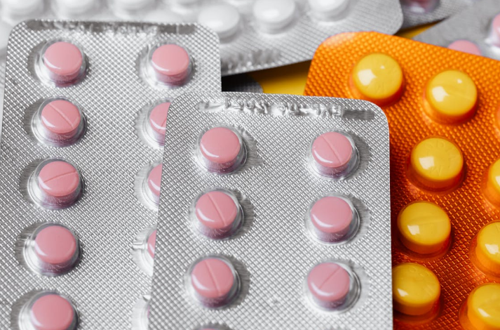 Close-up of several blister packs containing round pink and yellow pills.