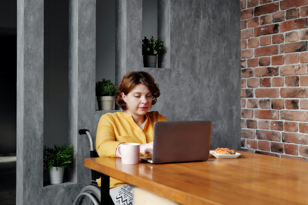 person in wheelchair using laptop on a desk