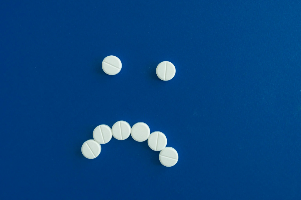 White pills arranged in a sad face on a blue background.
