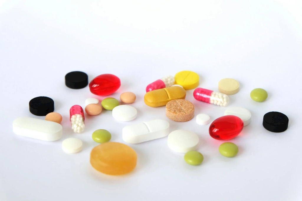 different pills and capsules of various shapes, sizes, and colors on a white background.