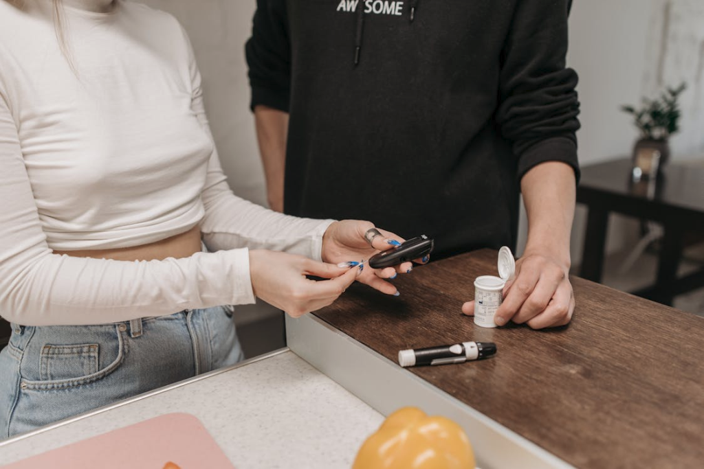 Close-up Shot of a Woman in Beige Long Sleeves Preparing the Glucose Meter