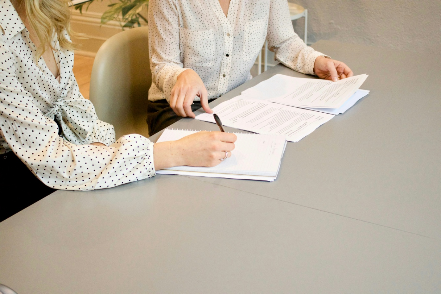 two people signing documents on a table