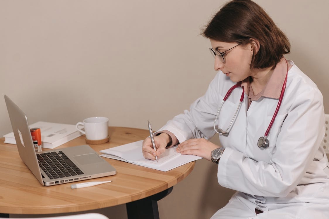 A doctor filling out medical forms at a table