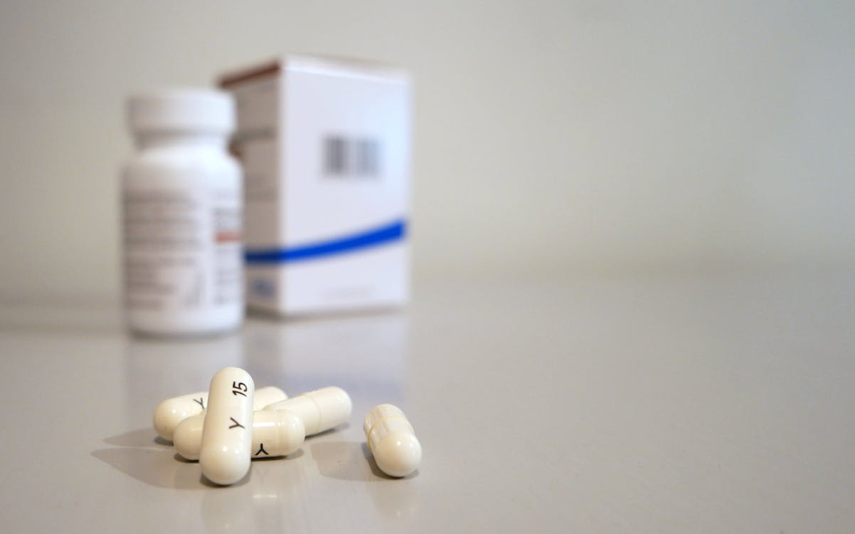 White capsules with a prescription bottle, representing affordable prescription drug assistance programs.