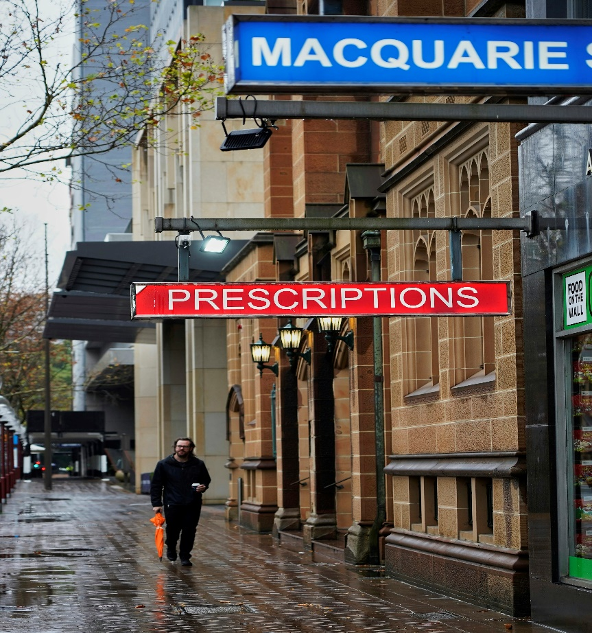 A person walking by a prescription store.