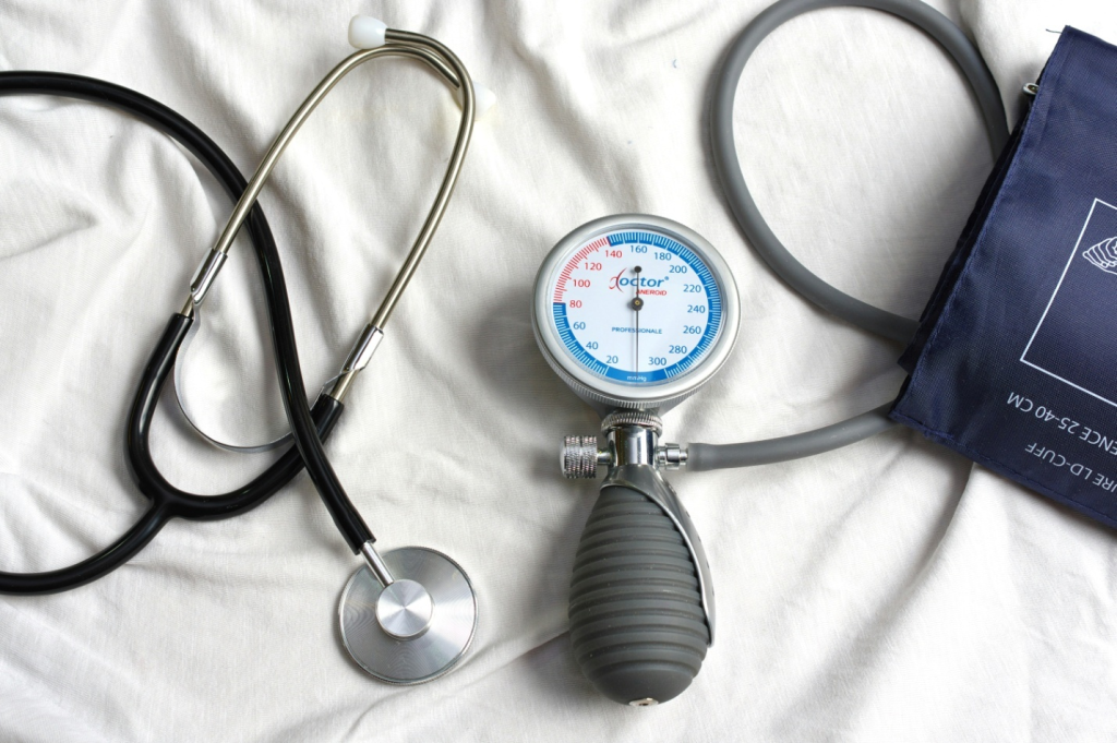 a blood pressure monitor and stethoscope on a white sheet