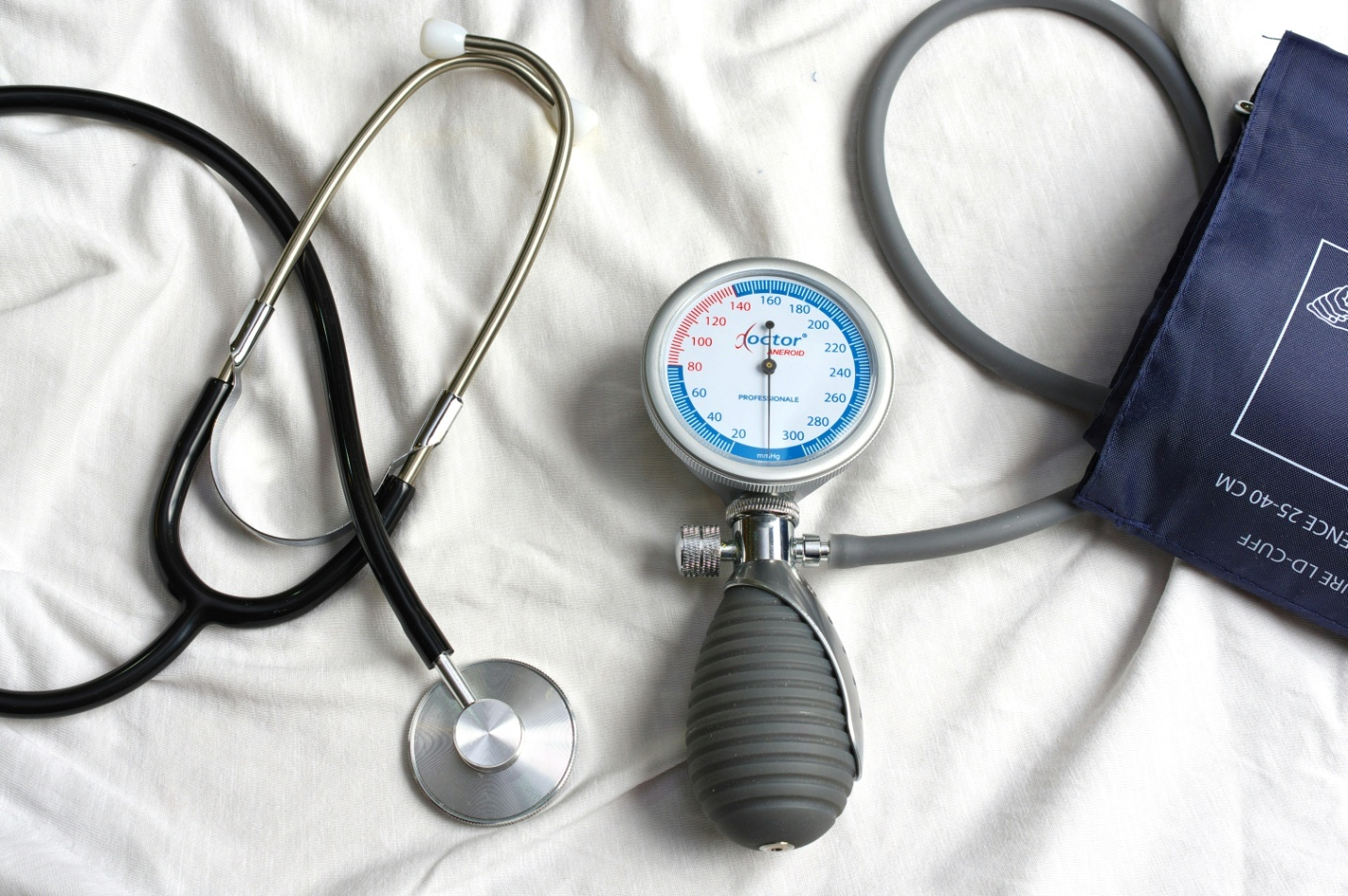 a blood pressure monitor and stethoscope on a white sheet