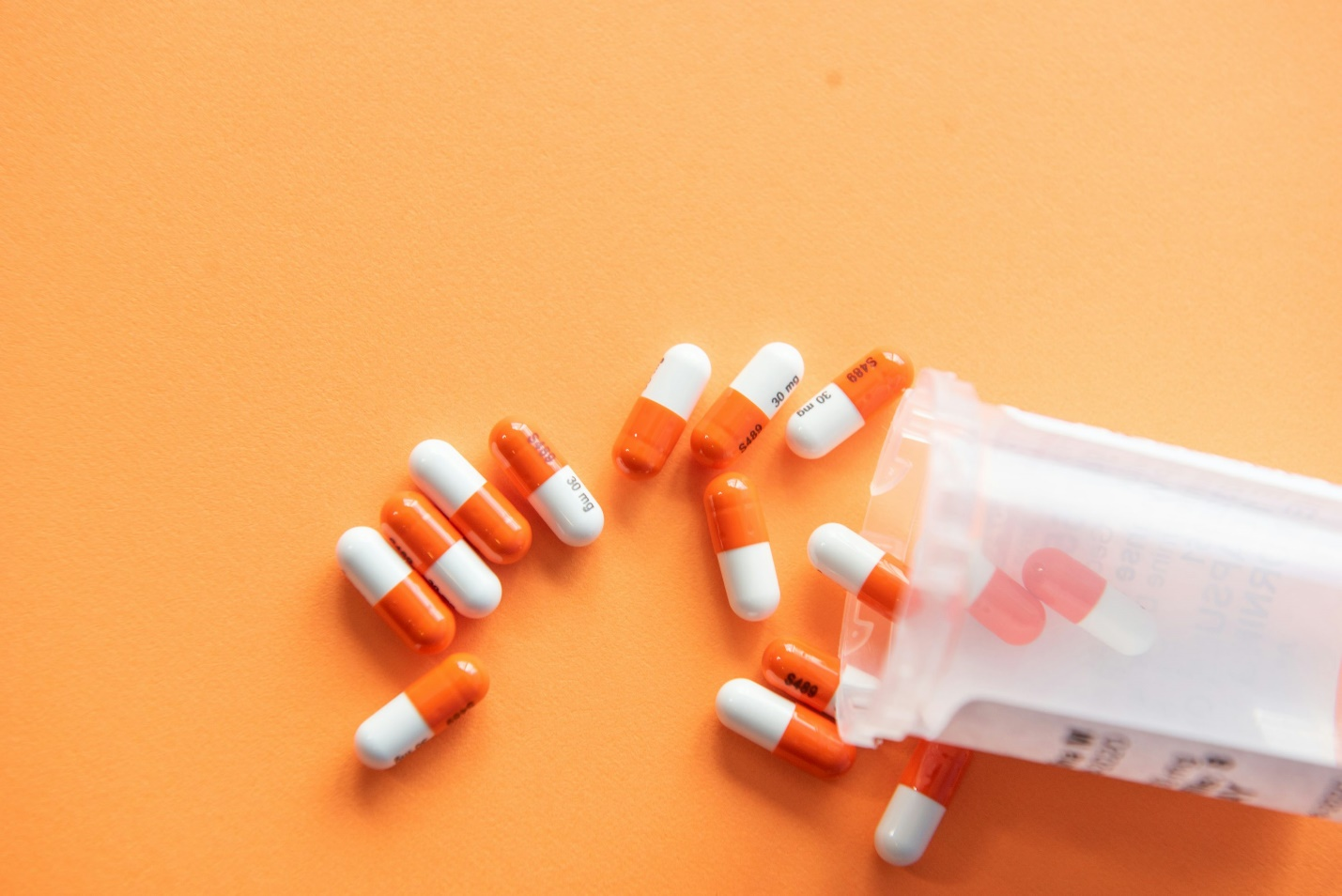 Several pills laid out on an orange table.