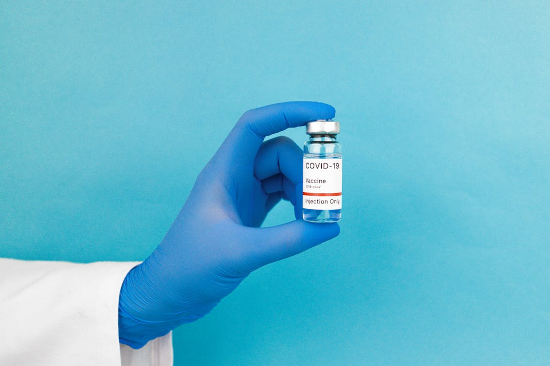 A person wearing blue gloves working with Pfizer medicine.