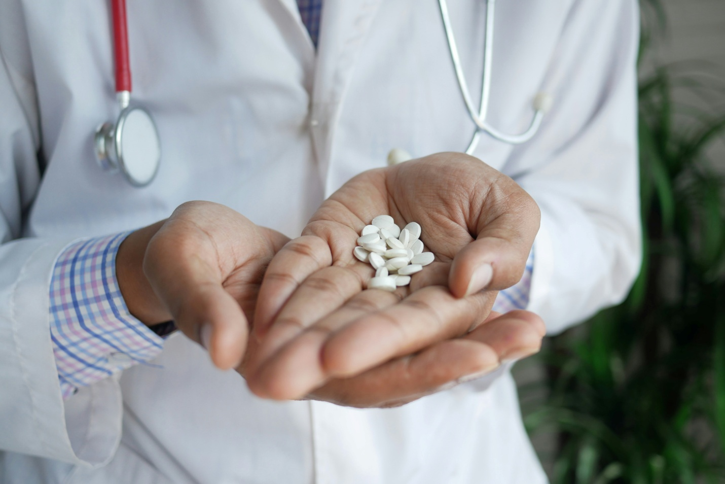 close-up image of a doctor’s hand holding white pills