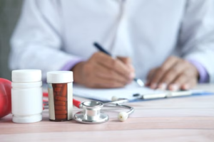 Doctor writing a prescription beside medicines and a stethoscope
