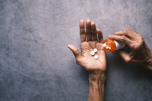 Senior woman holding a prescription pill while managing her medication