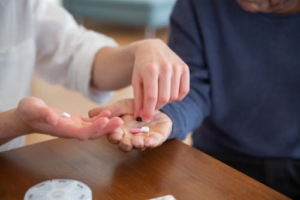 Hands passing prescription medicine to another person