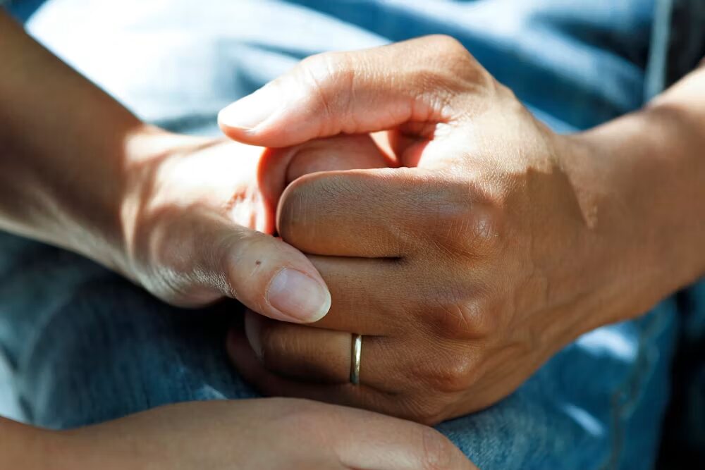 A patient in a blue gown holding hands with someone