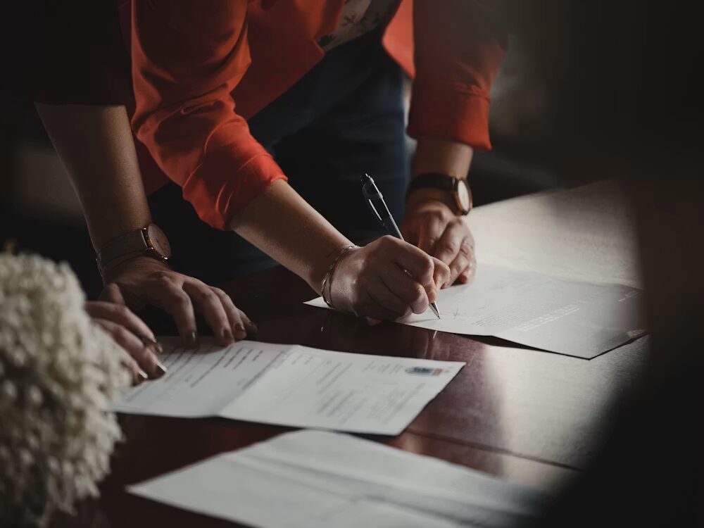 Two people filling in paperwork on a table