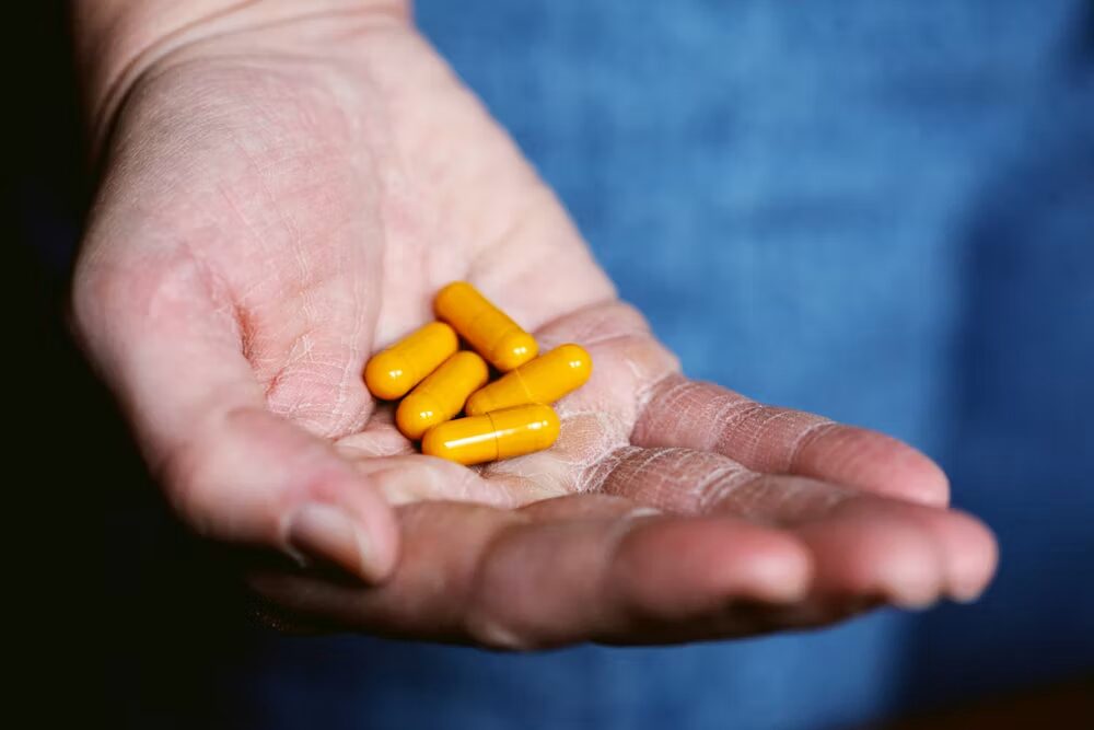  Yellow pills on a person’s hand