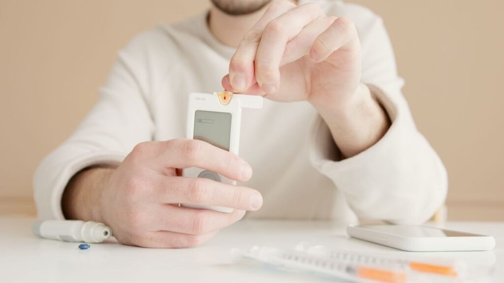 An image of a man using a blood glucose monitor
