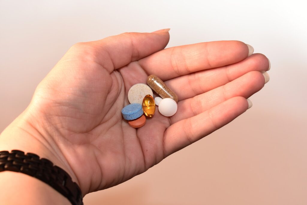 Hand holding multiple prescription medications, representing patient assistance programs that help eligible individuals afford necessary treatments.