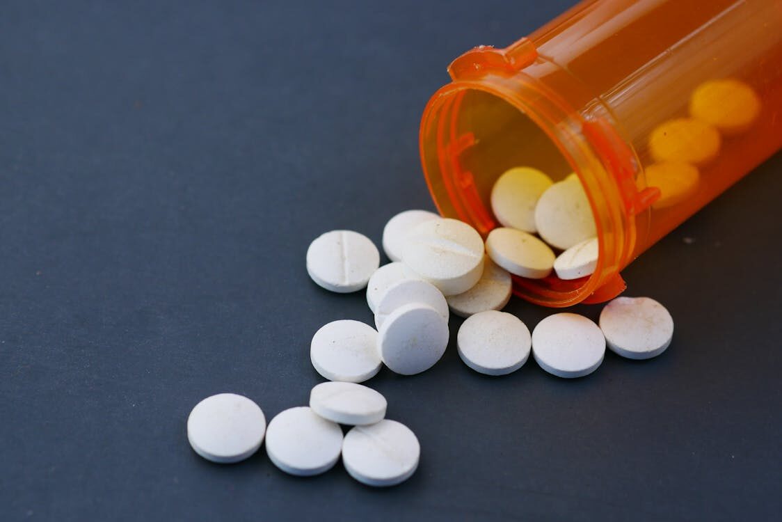 tablets coming out of an orange medicine bottle